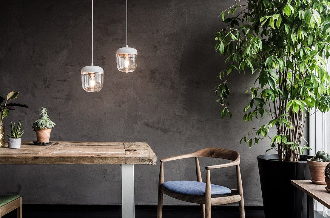 A dining room with a wooden table and chairs and potted plants.