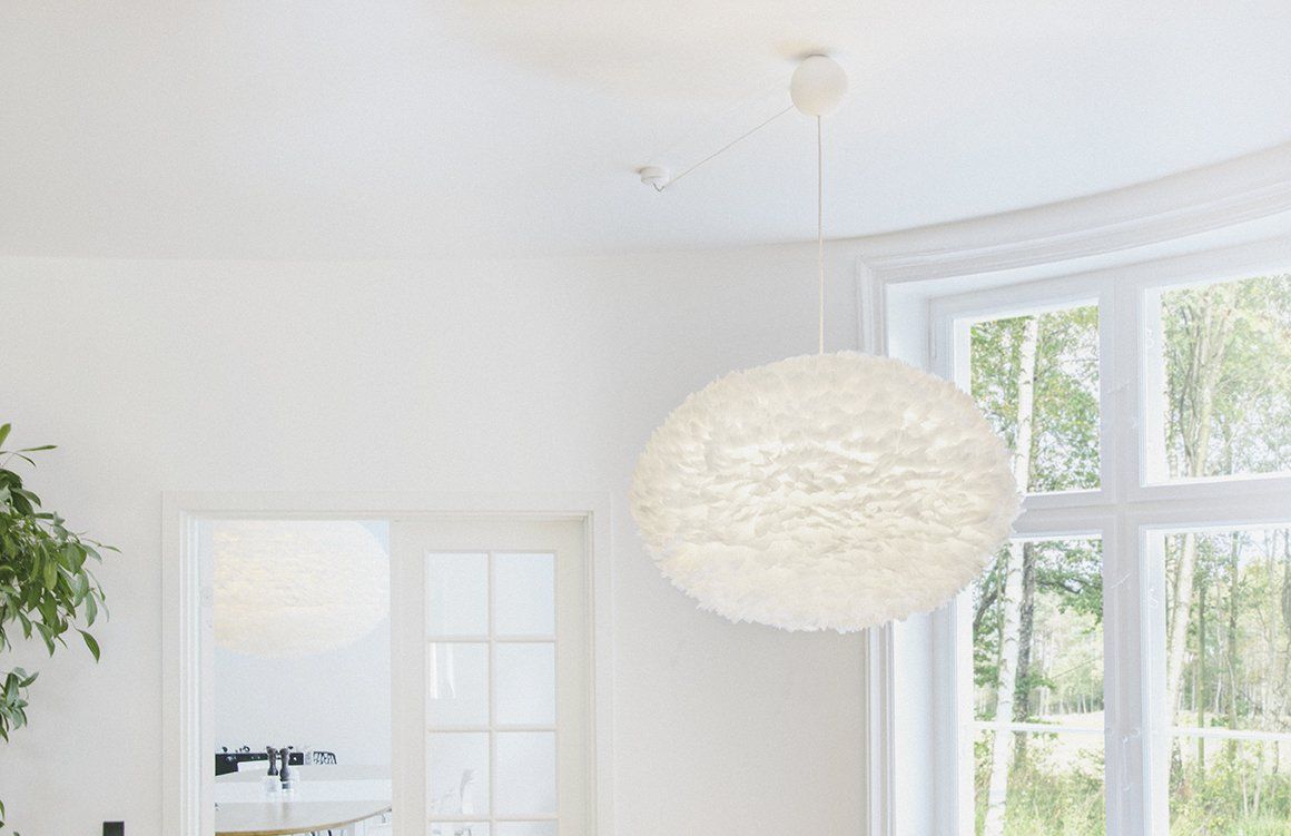 A white pendant light is hanging from the ceiling in a room with a large window.