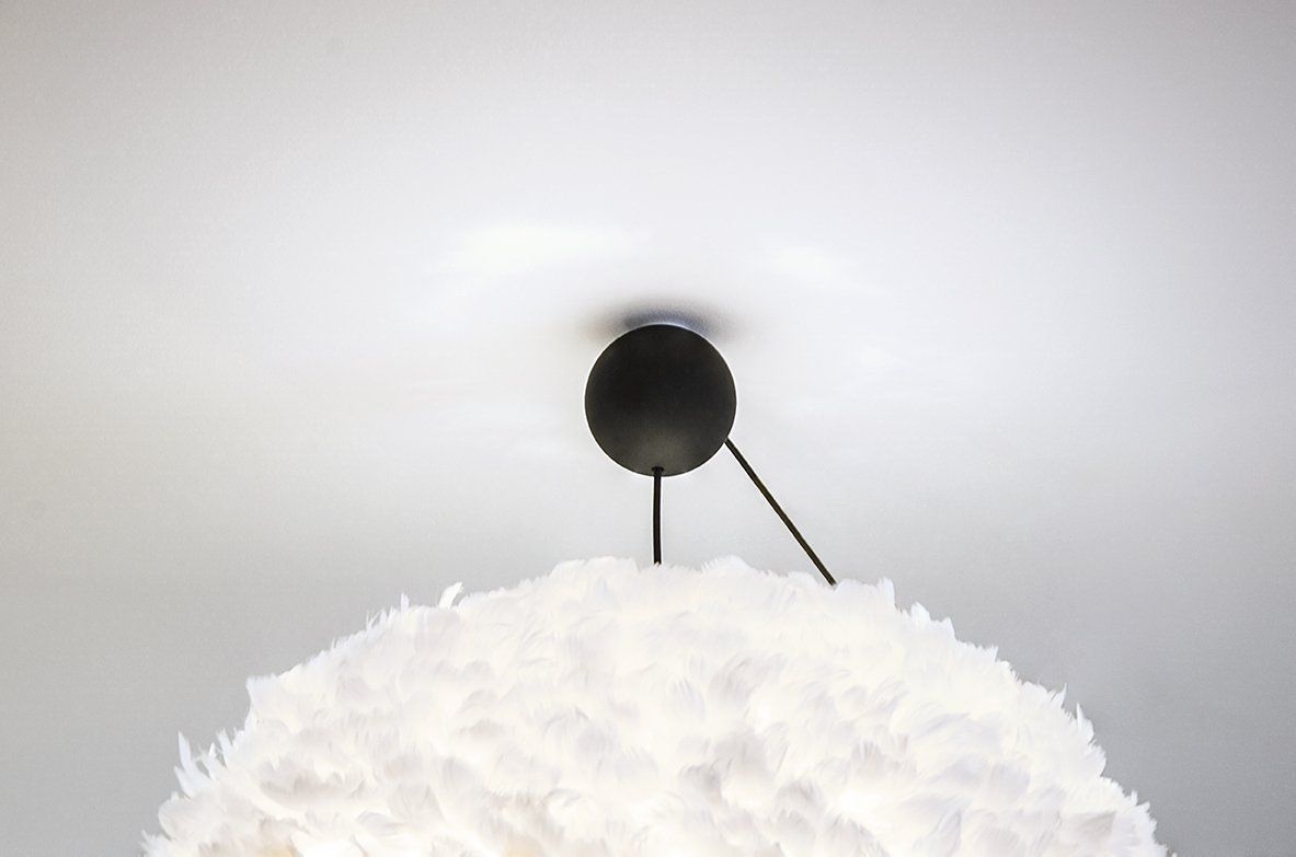 A close up of a white feather lamp hanging from the ceiling.