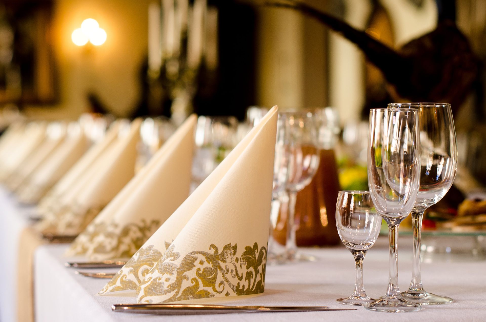 A long table with wine glasses and napkins on it