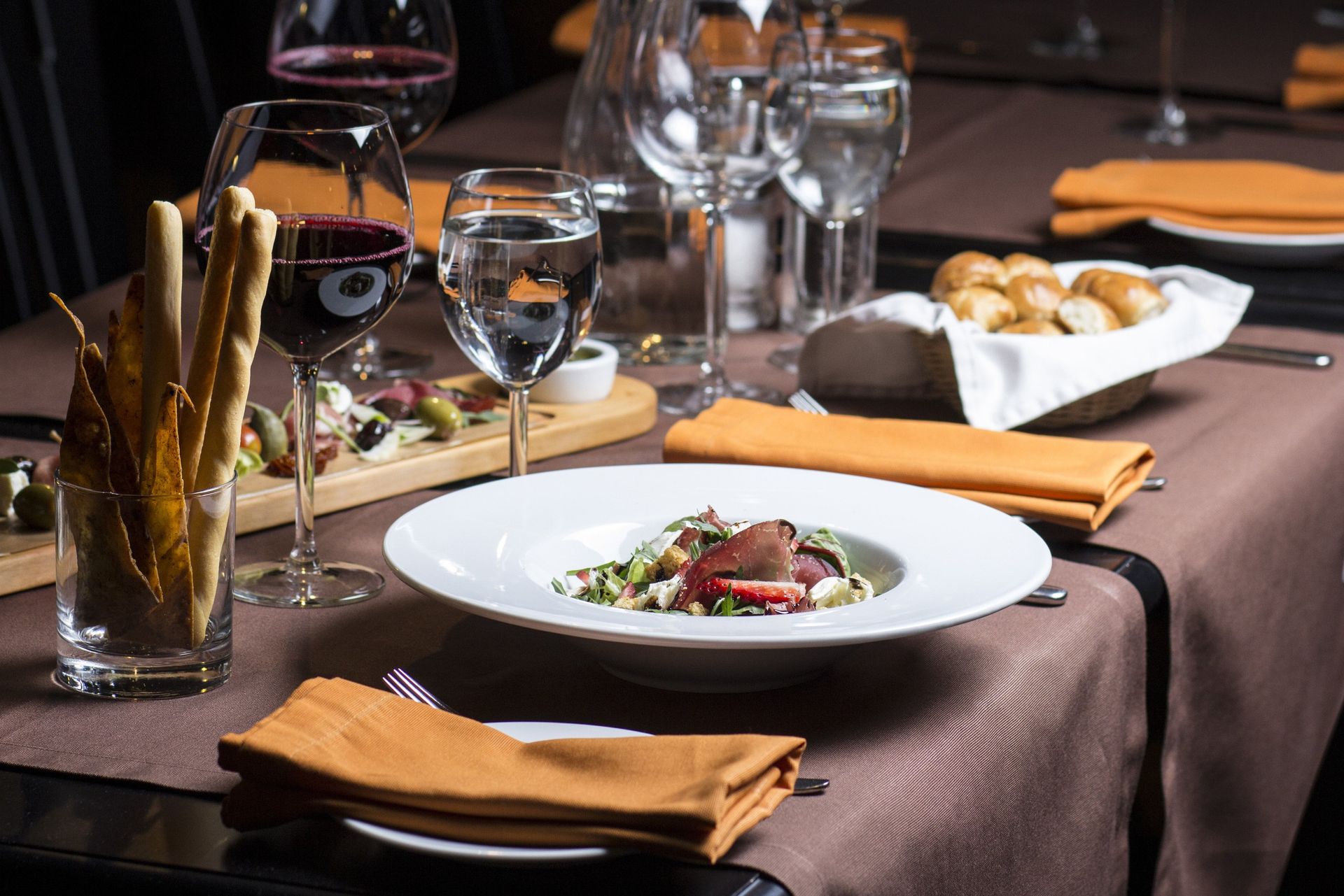 A table with plates of food and wine glasses on it.