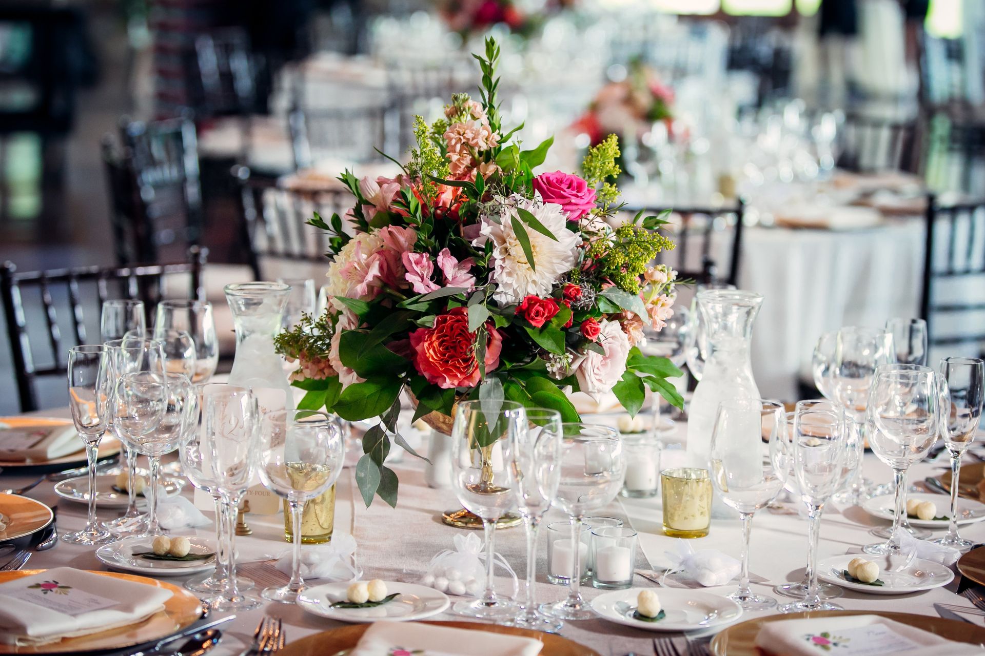 A table set for a wedding reception with a vase of flowers on it.