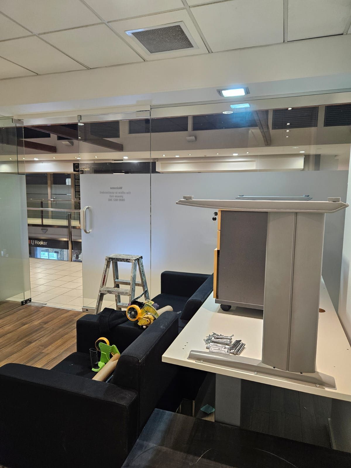 Interior office space under construction with furniture and tools present.