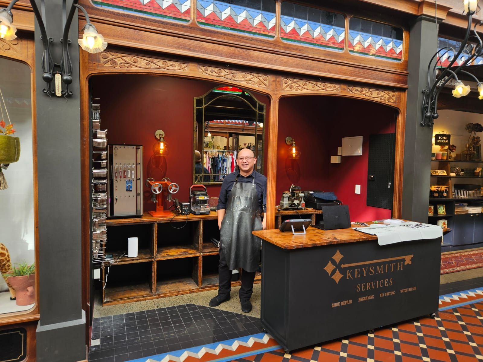 Full-length mirror in a shoe store. White wall with black dot pattern, black frame, wooden floor, shoe displays.