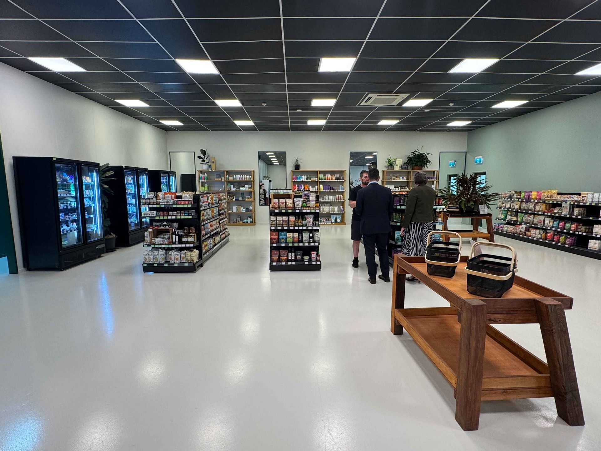 Inside a well-lit store, shelves stocked with products, customers and employees browse the aisles.