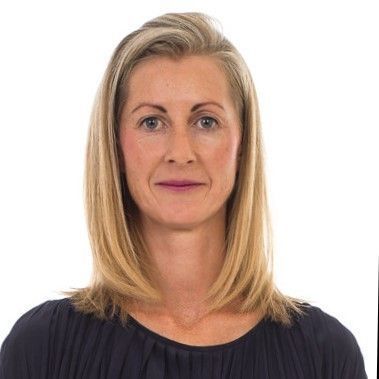 Blonde woman with shoulder-length hair, wearing a dark top, facing the camera.