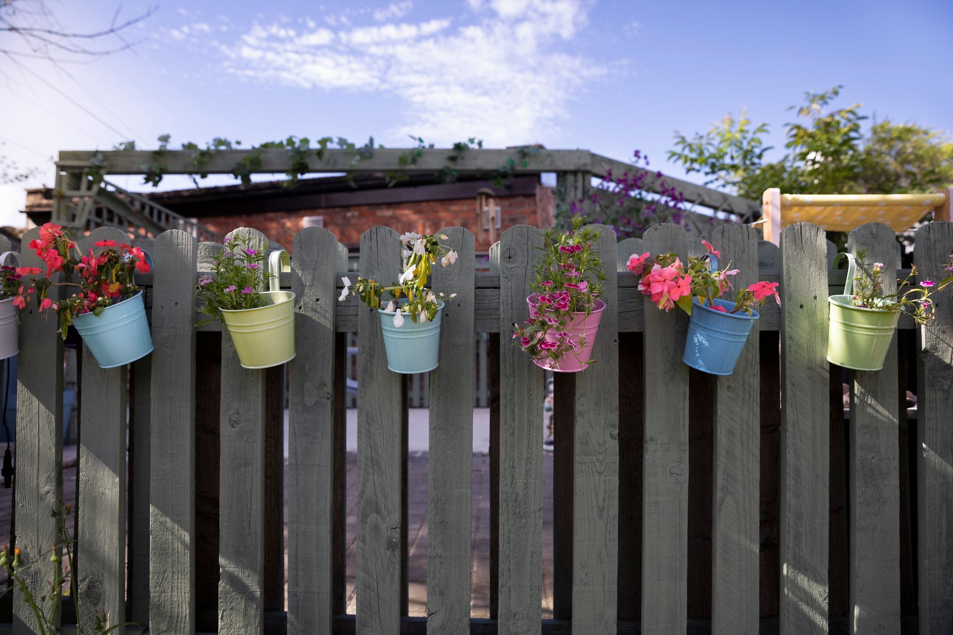 A wooden fence with potted plants hanging from it.