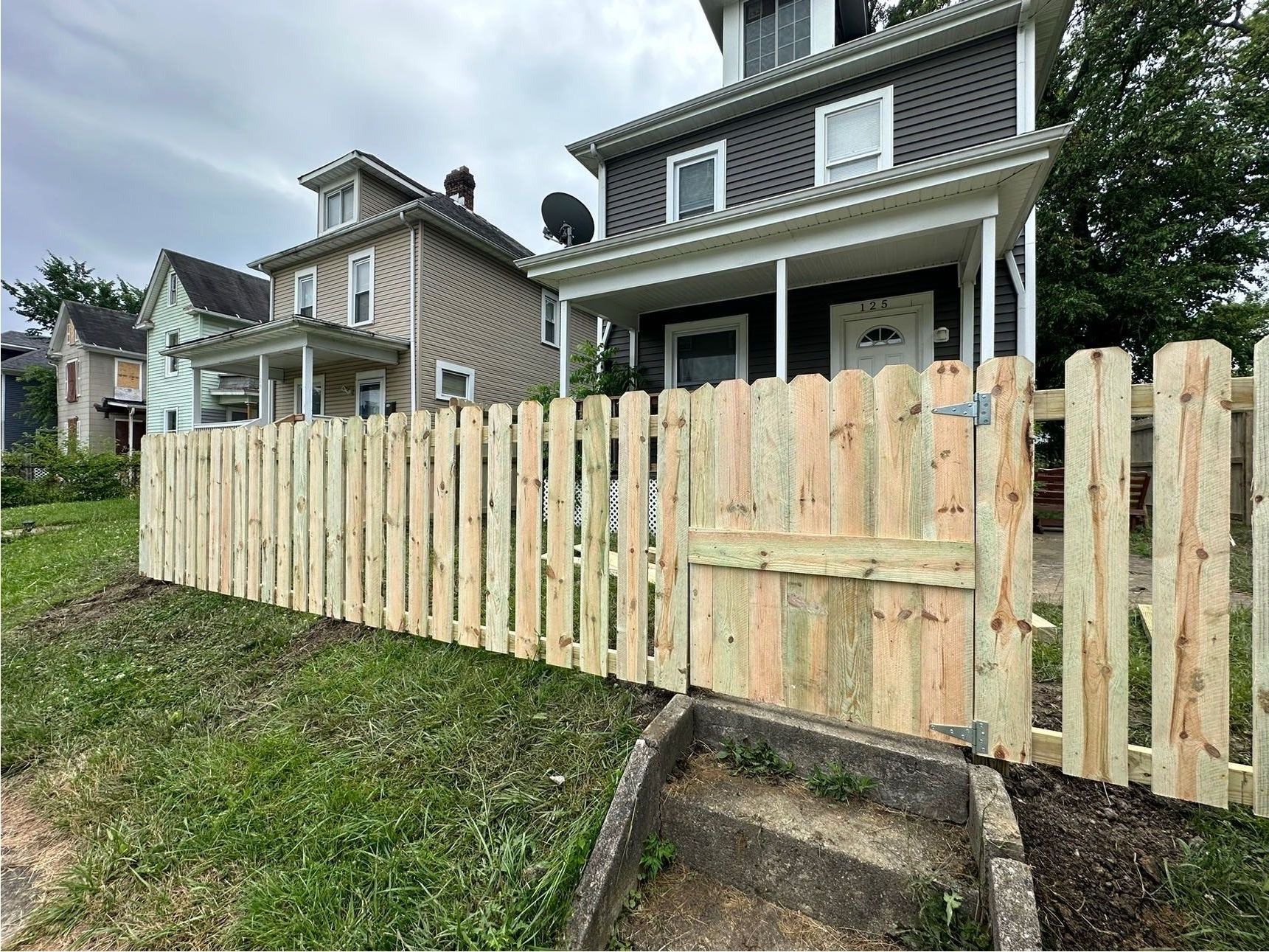 A wooden fence is along the side of a road.