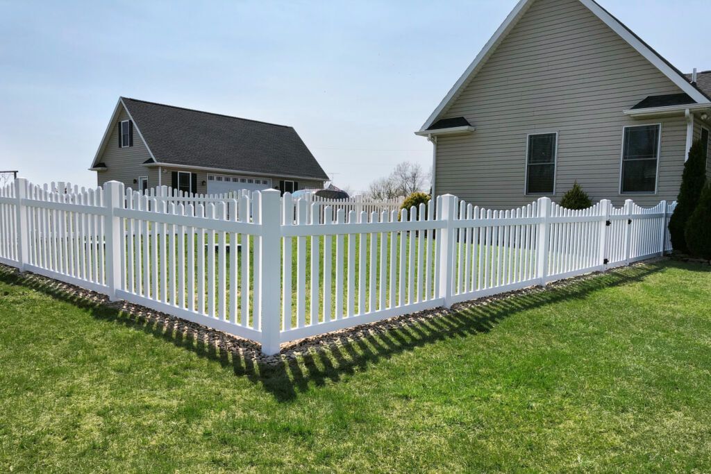 A white picket fence surrounds a lush green field.