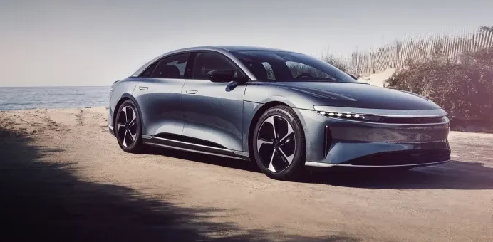 Silver Lucid Air electric car on a beach road.