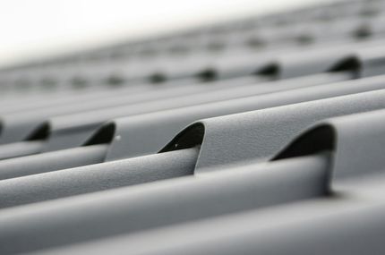 Close-up of gray corrugated metal roofing, with a blurred background.