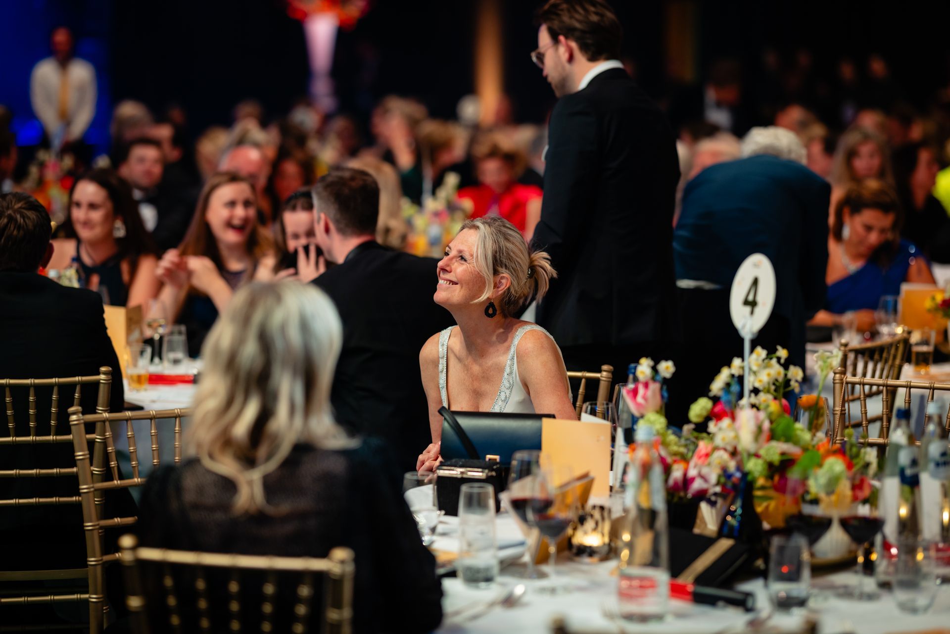 A group of people are sitting at tables at a dinner party.