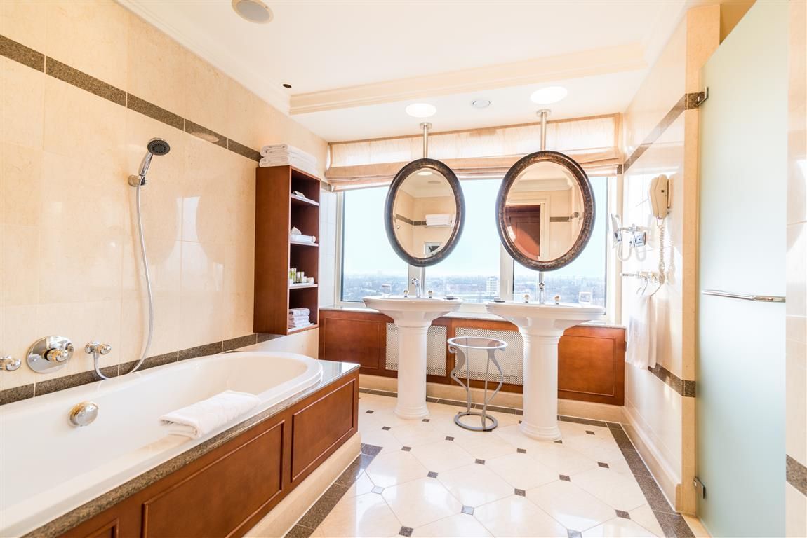 A bathroom with a tub , sink and mirrors.