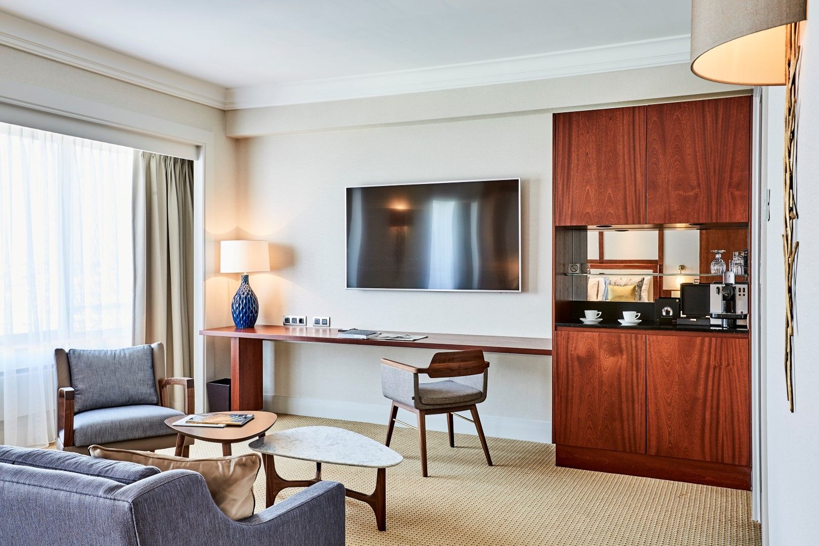 A living room in a hotel room with a couch , chair , desk and television.