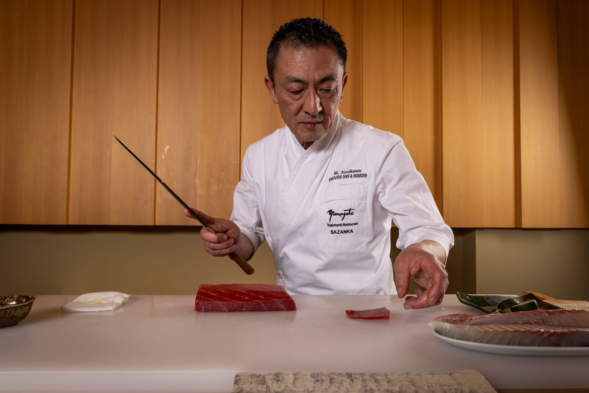 A chef is cutting a piece of meat on a cutting board.
