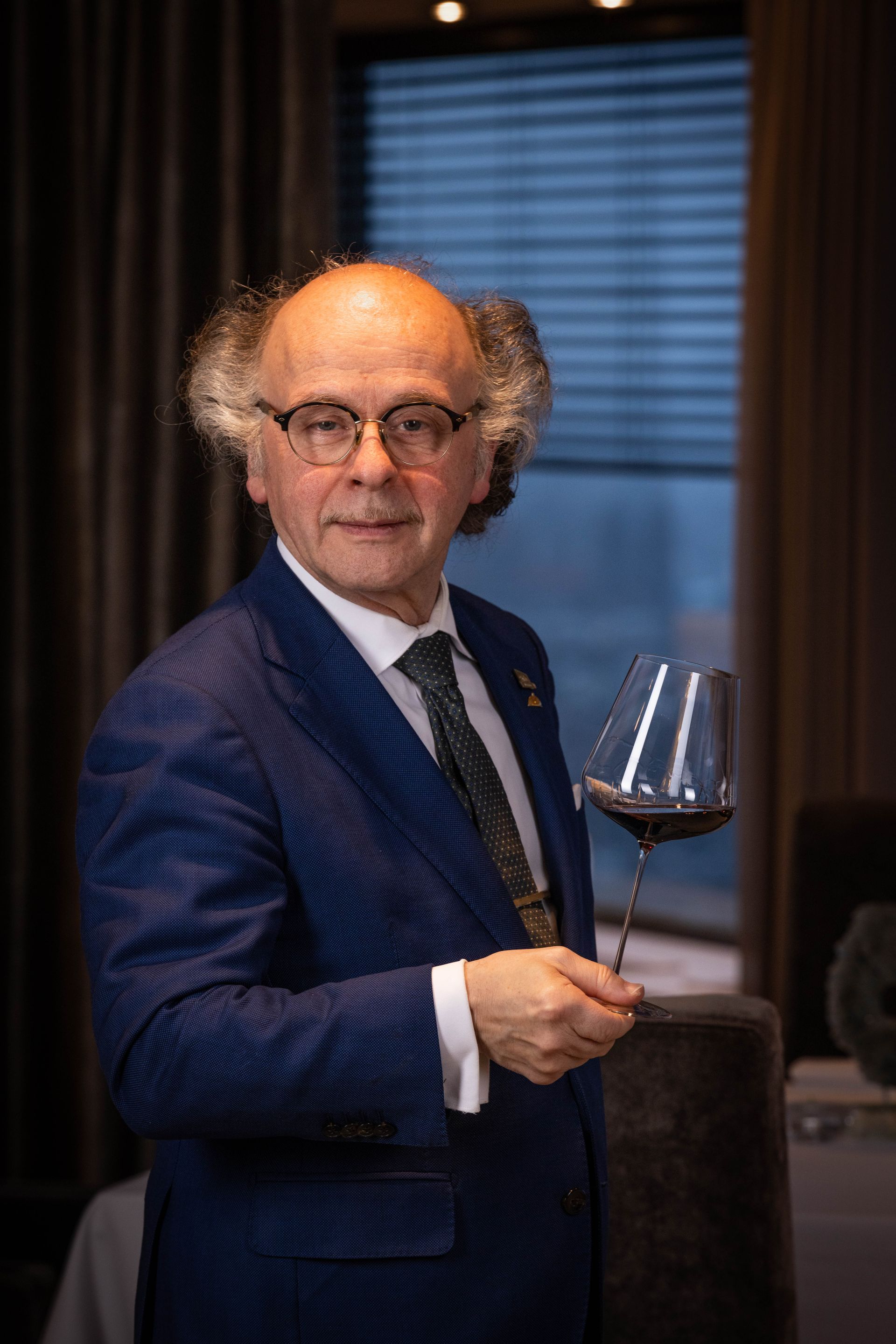 A man in a suit and tie is holding a glass of wine.