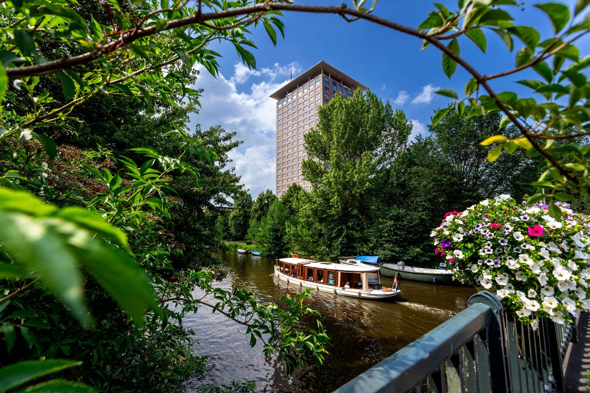 A boat is floating on a river with a tall building in the background.