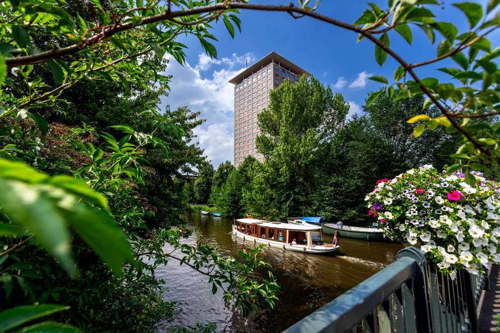 A boat is floating on a river with a tall building in the background.