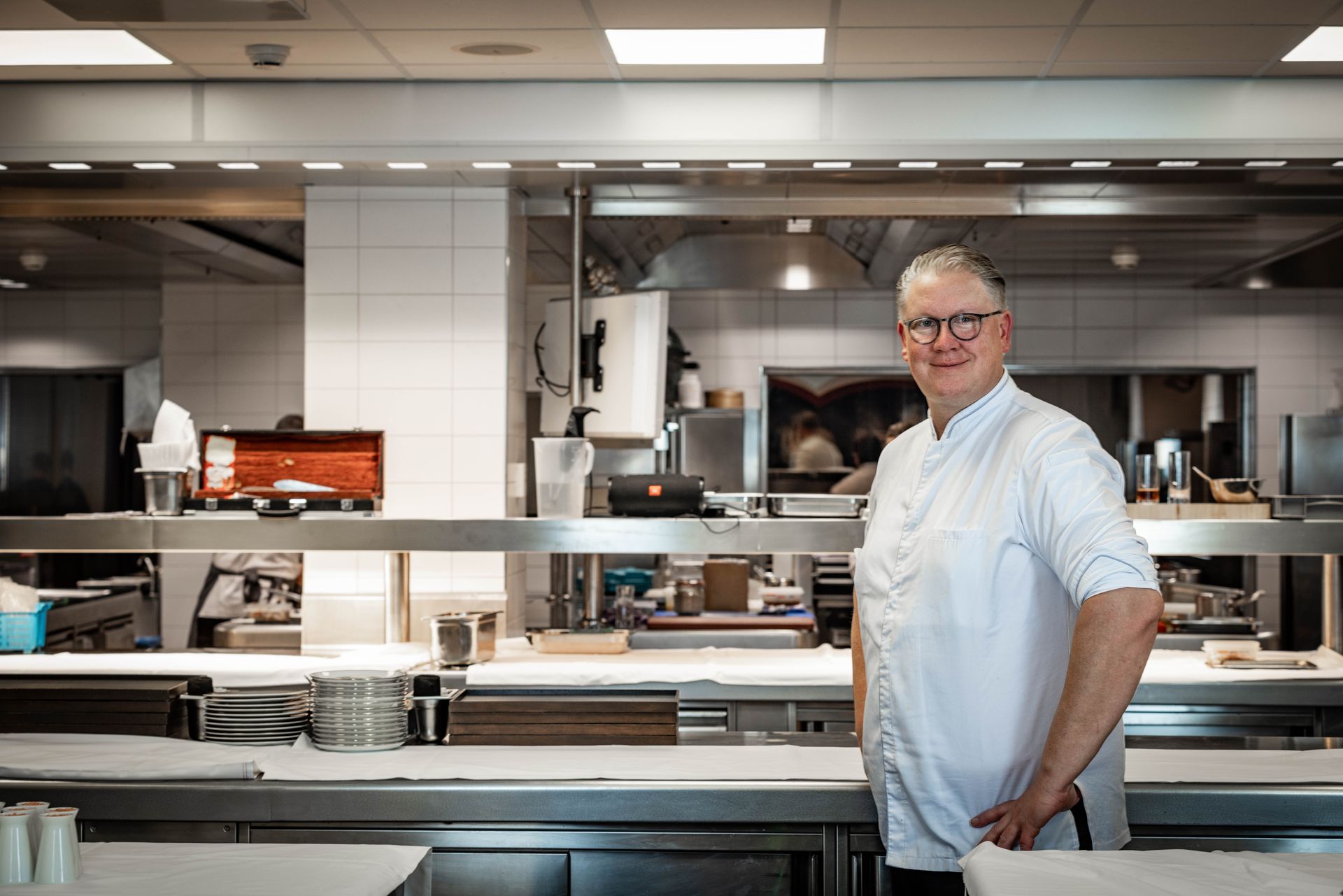 A man is standing in a kitchen with his hands on his hips.