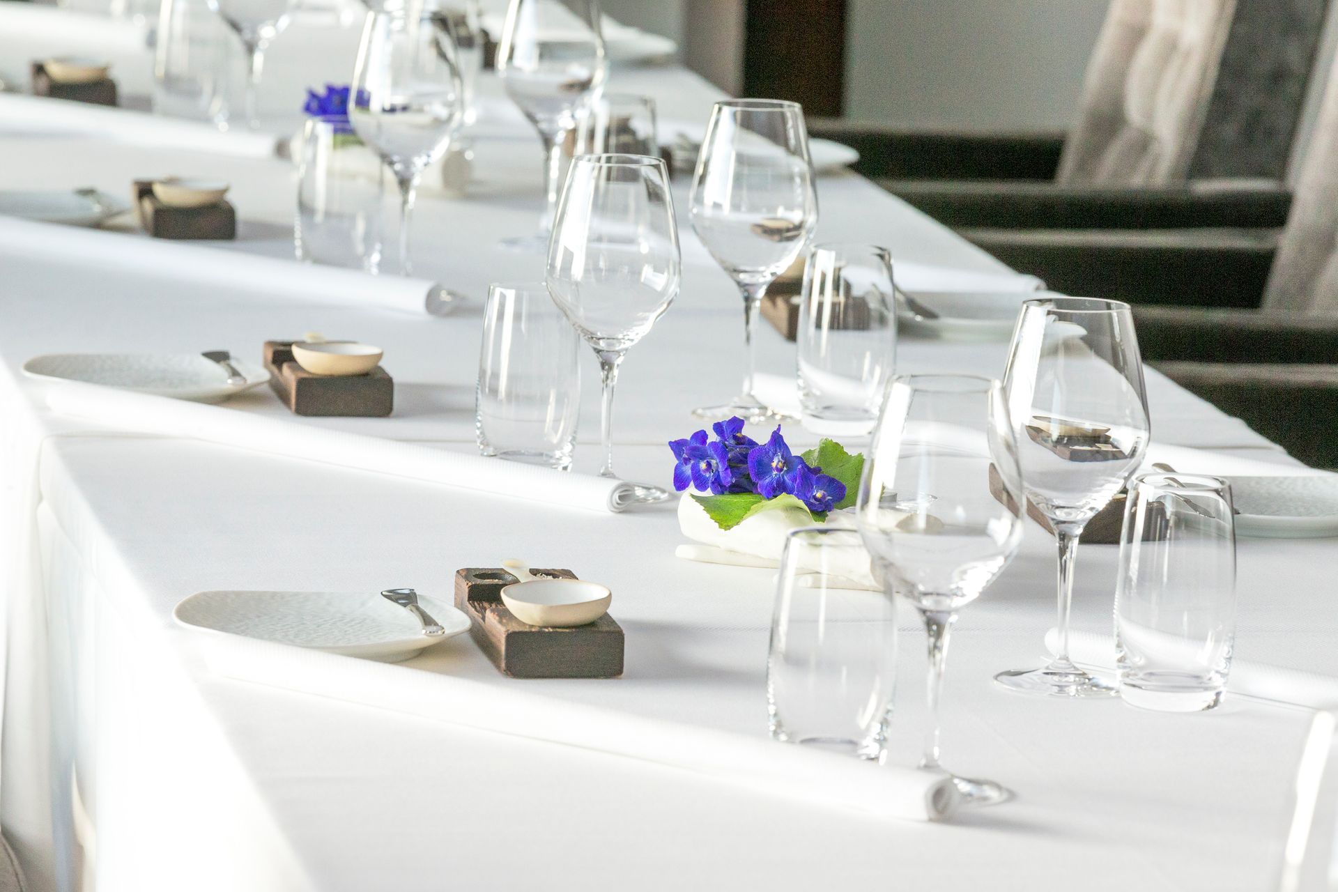 A long table with a white tablecloth and wine glasses on it.