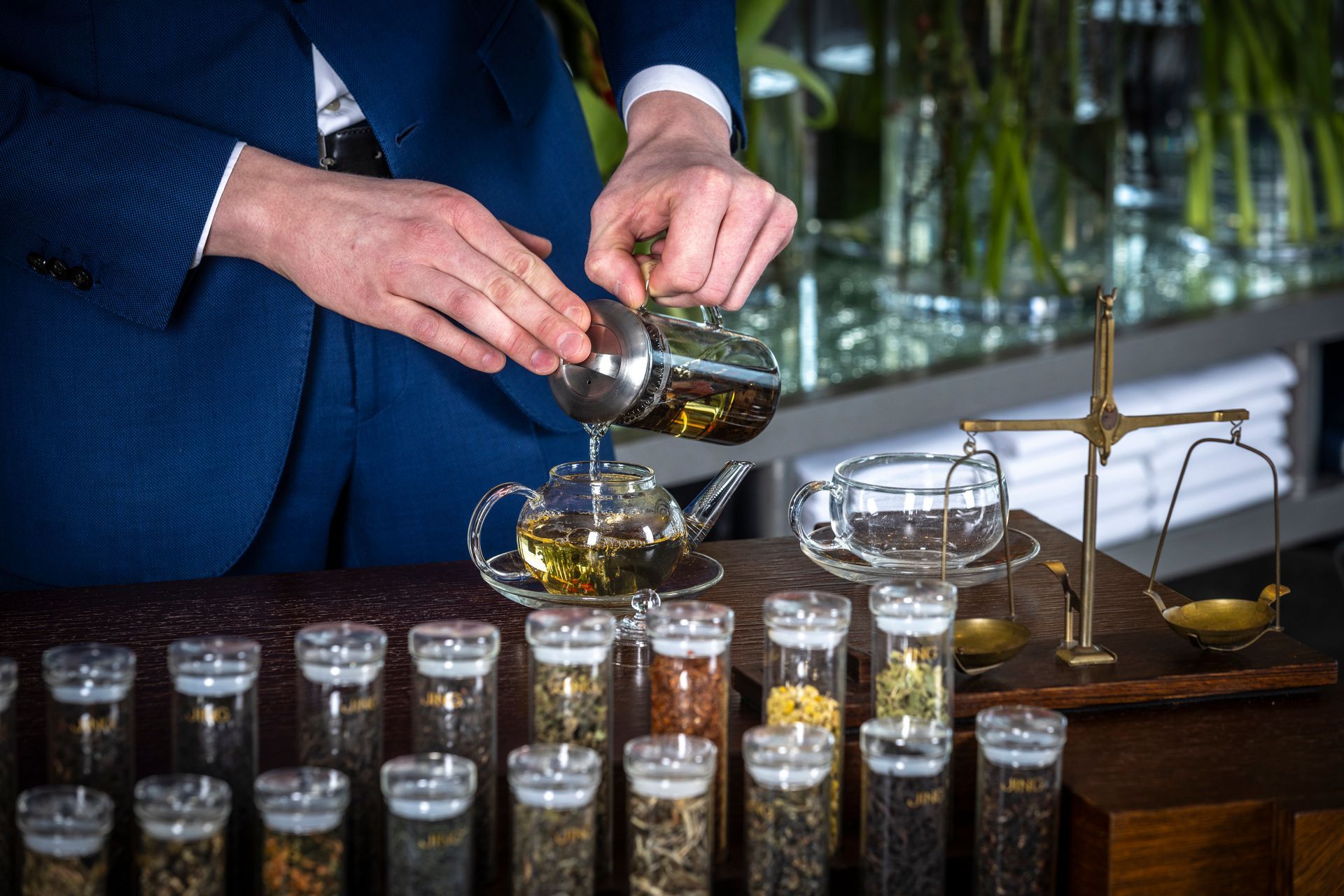 A man in a suit is pouring tea into a cup.