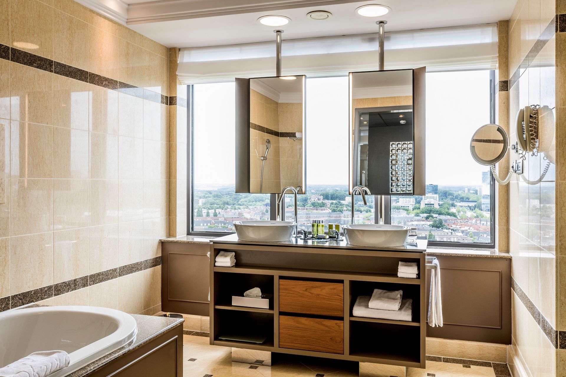 Een badkamer met twee wastafels, een bad en een groot raam.