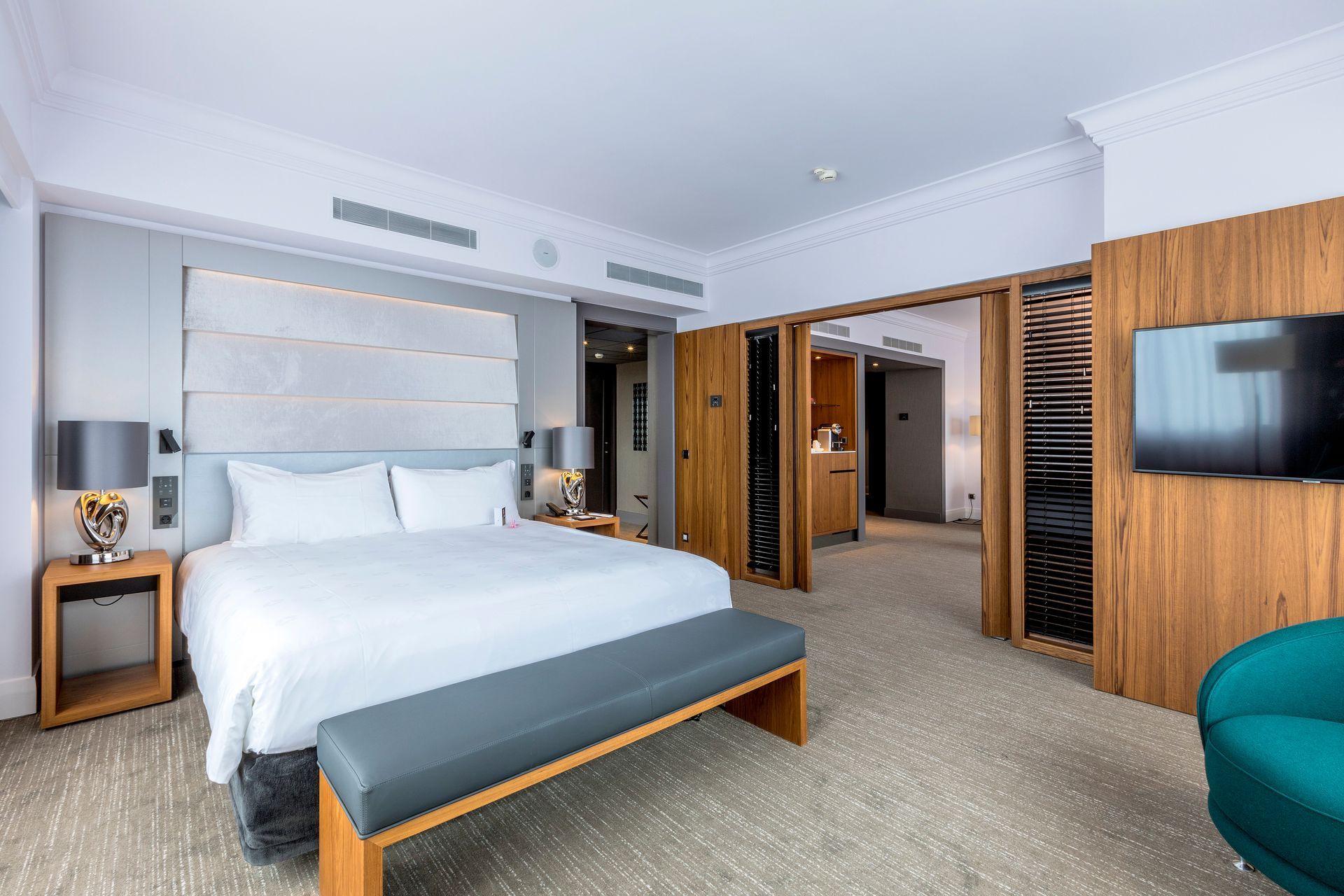 A hotel room with a king size bed and a bench.