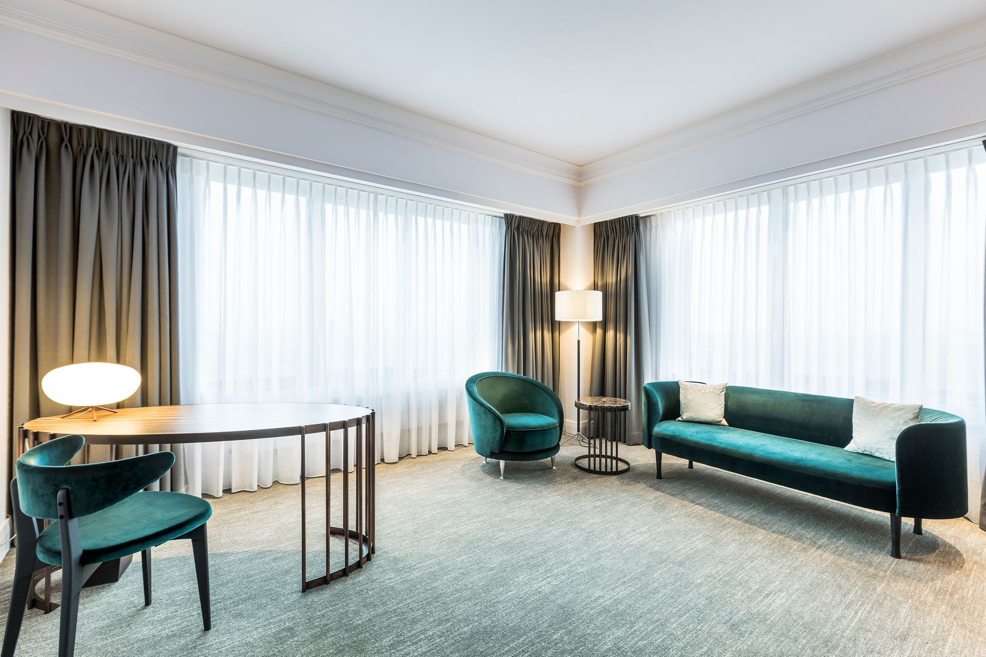 A hotel room with a couch , chairs , and a desk.