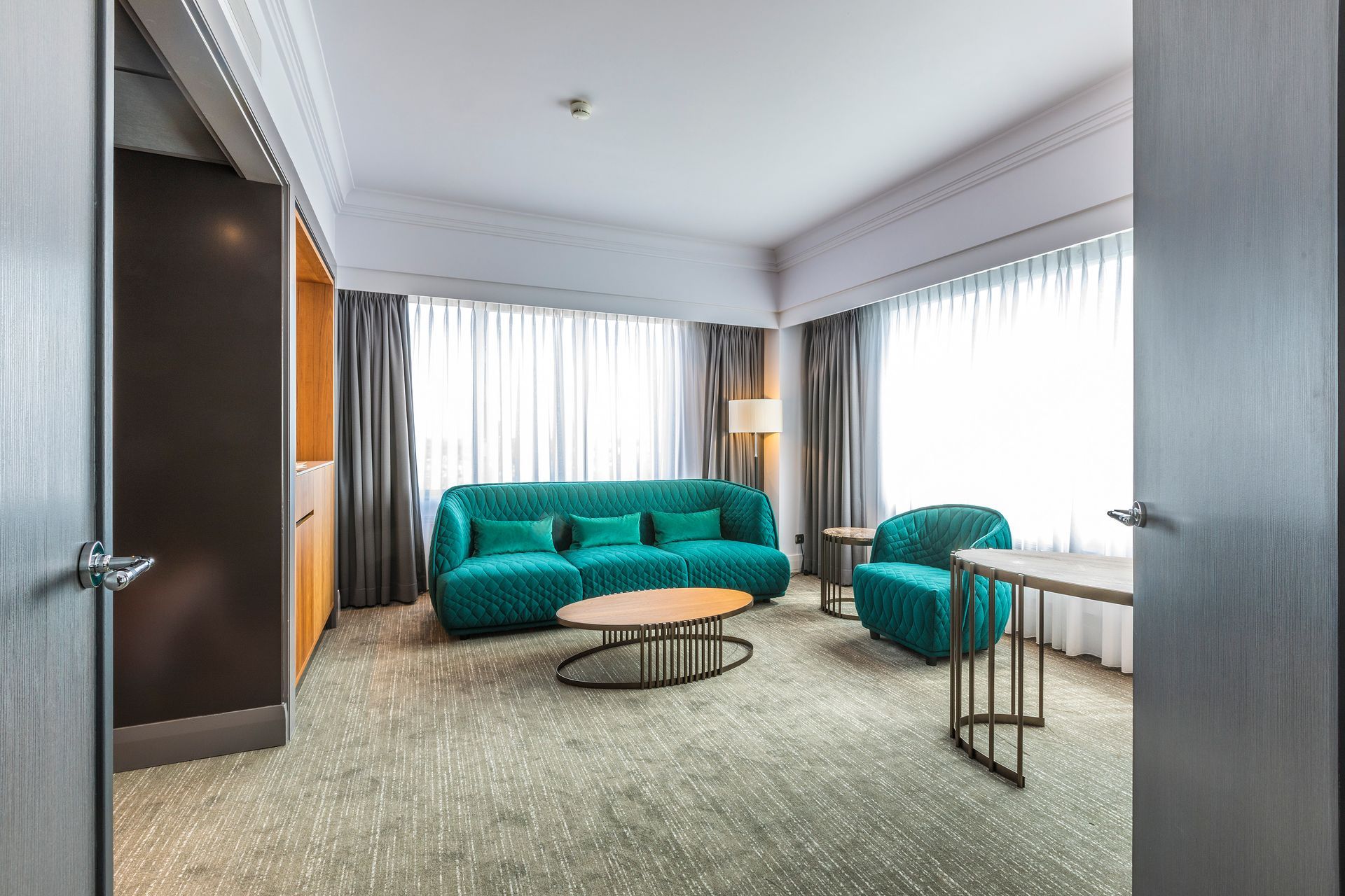 Een hotelkamer met een bank, stoel, tafel en raam.