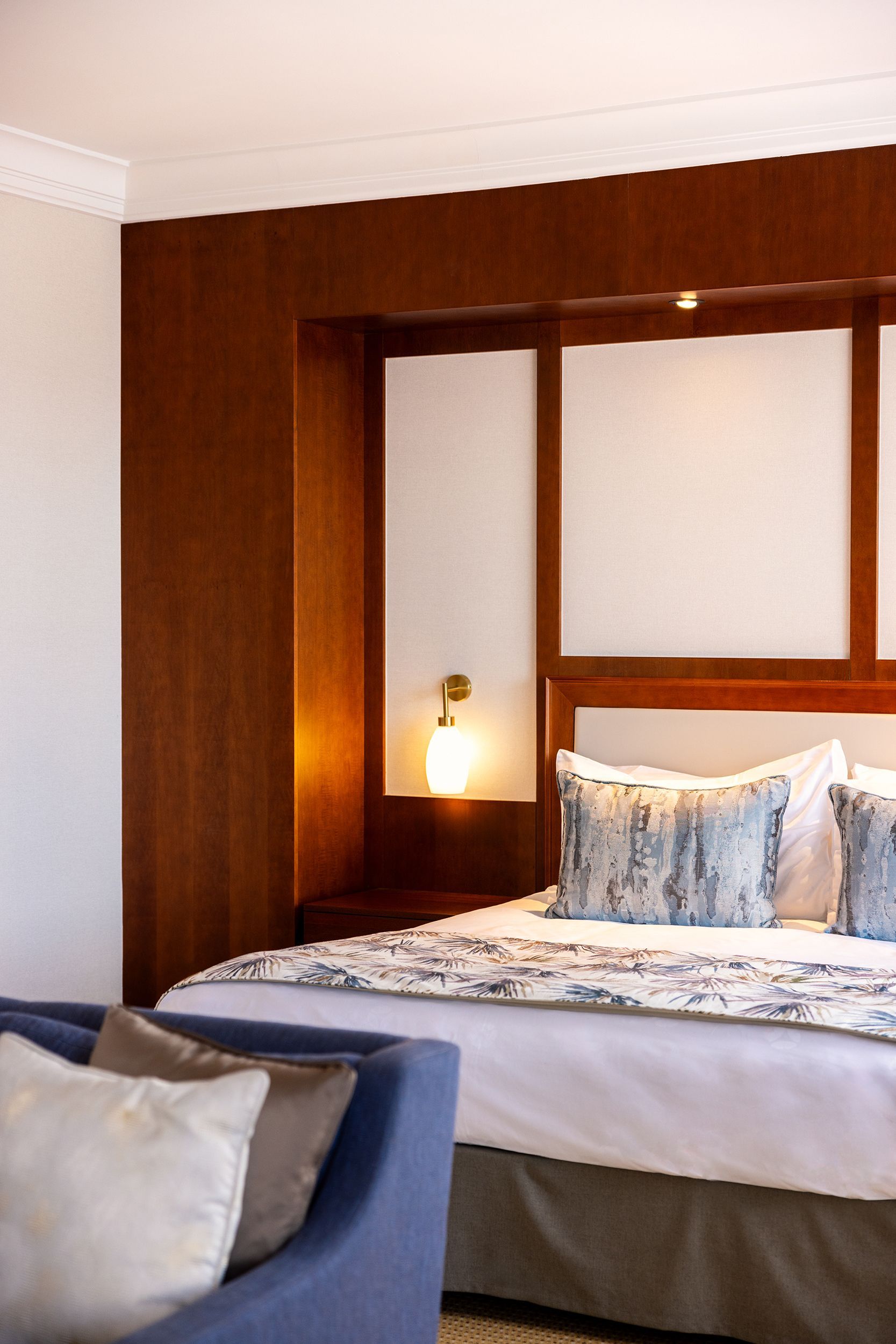 A hotel room with a large bed and a blue chair