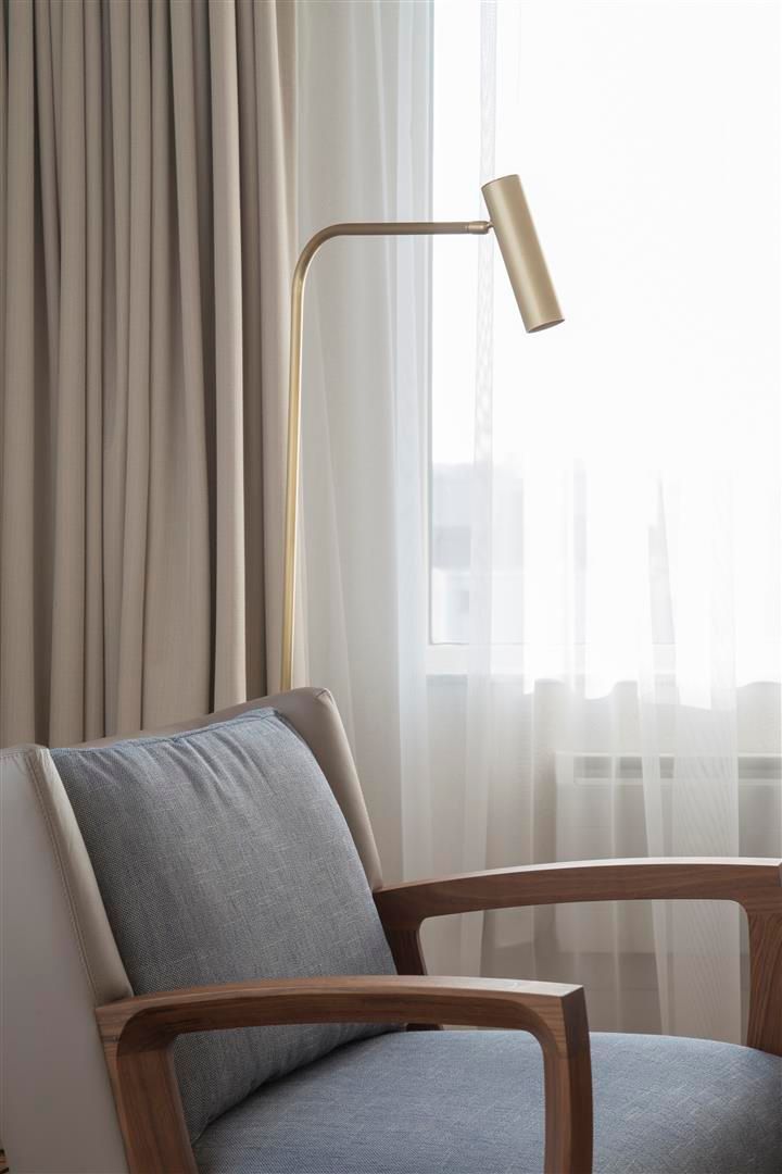 A chair is sitting in front of a window next to a lamp.