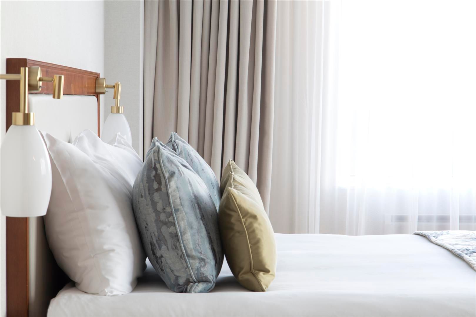 A bed with white sheets and pillows in a hotel room.
