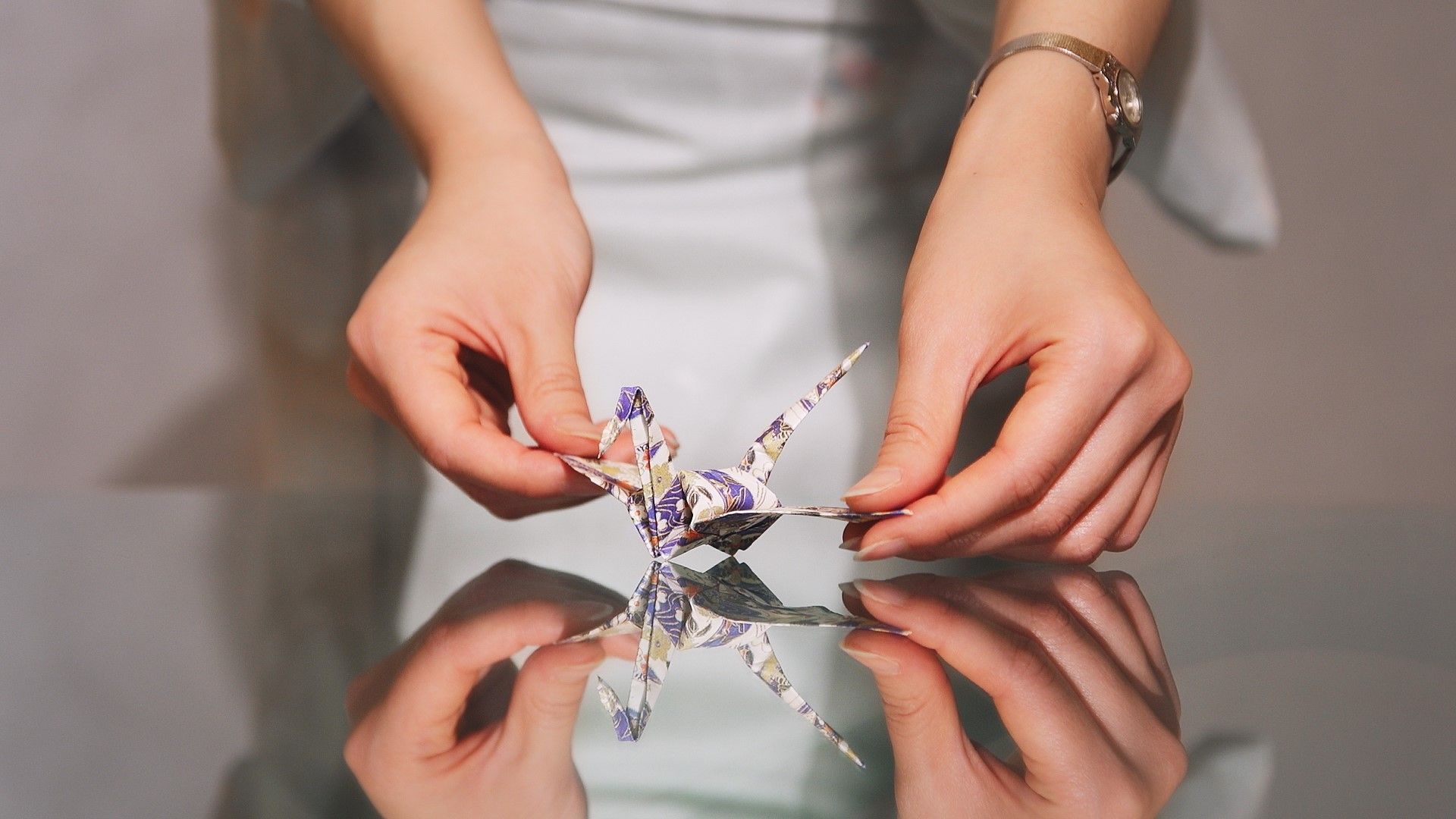 A woman is holding an origami bird in her hands.