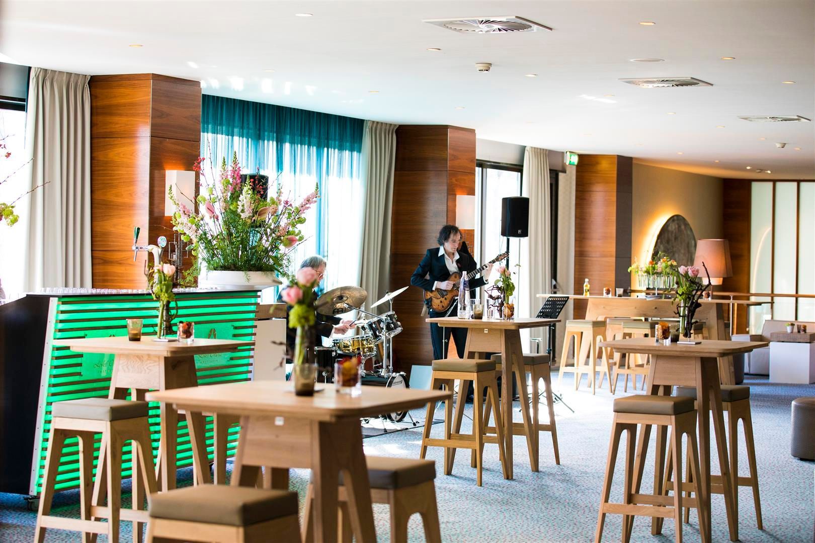 A man is playing a guitar in a restaurant with tables and chairs.