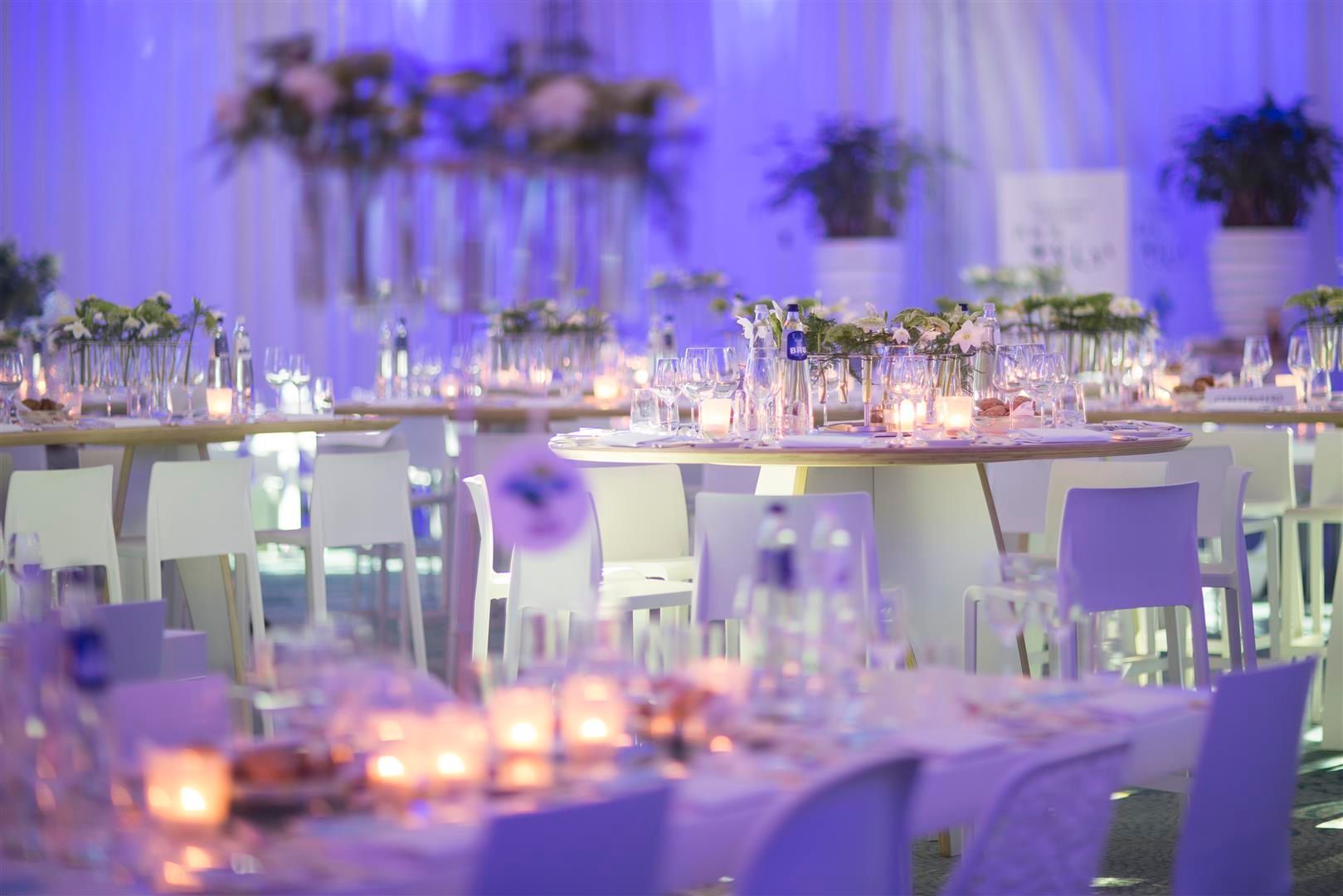 A room filled with tables and chairs set up for a wedding reception.