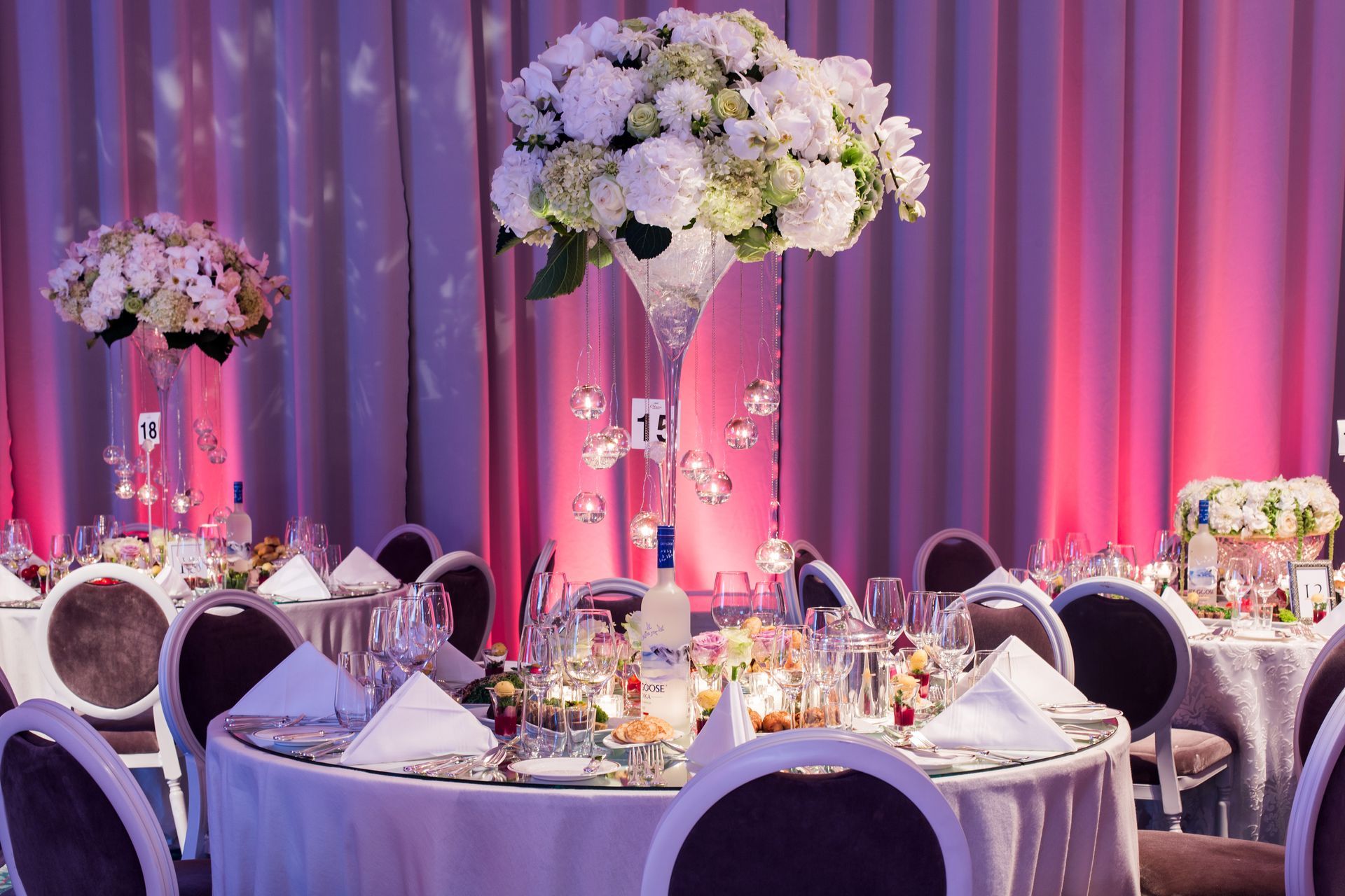 A table set for a wedding reception with a vase of flowers on it.