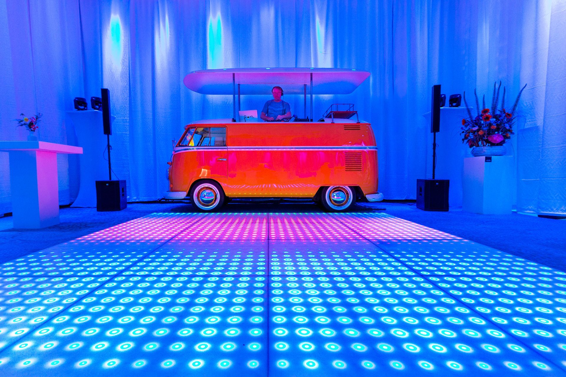 A dj is playing music in a van on a dance floor.