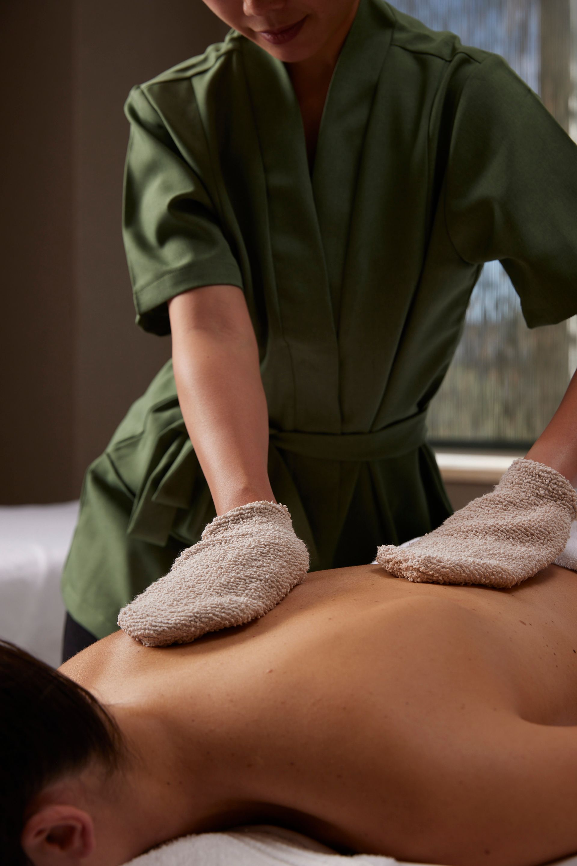 Een vrouw krijgt een massage in een spa met handschoenen aan.