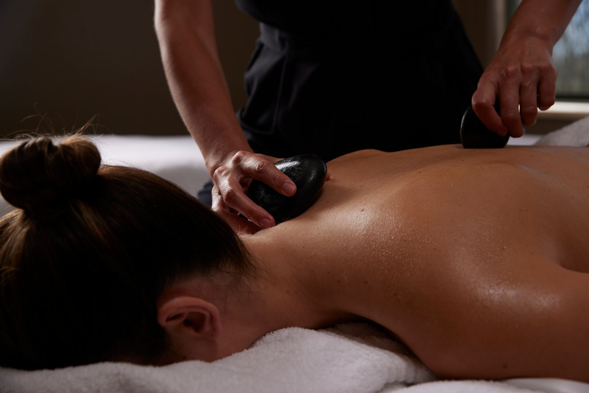 A woman is getting a hot stone massage at a spa.