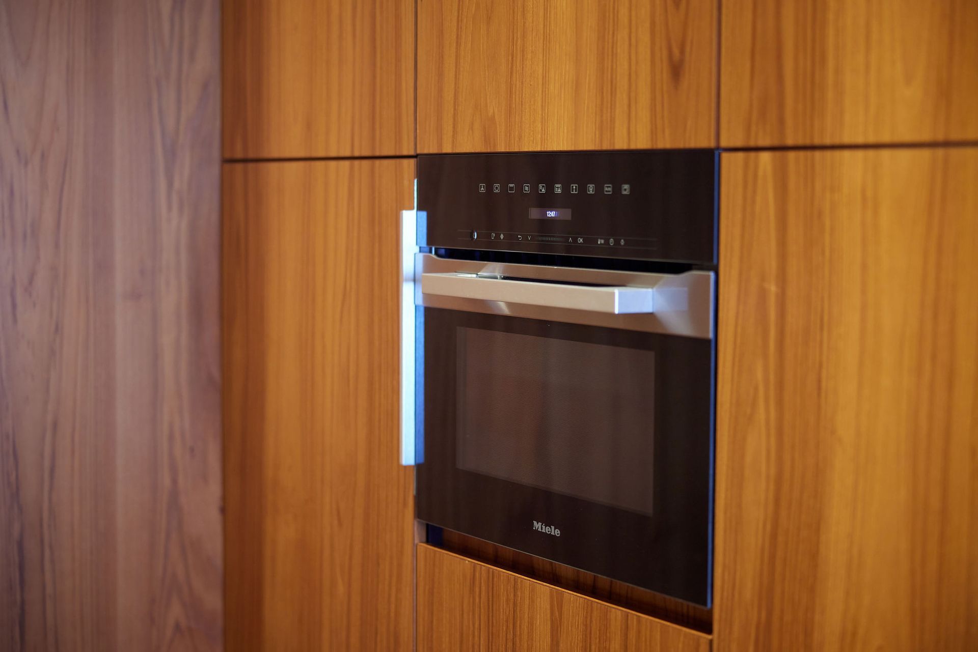 A microwave oven is built into a wooden cabinet in a kitchen.