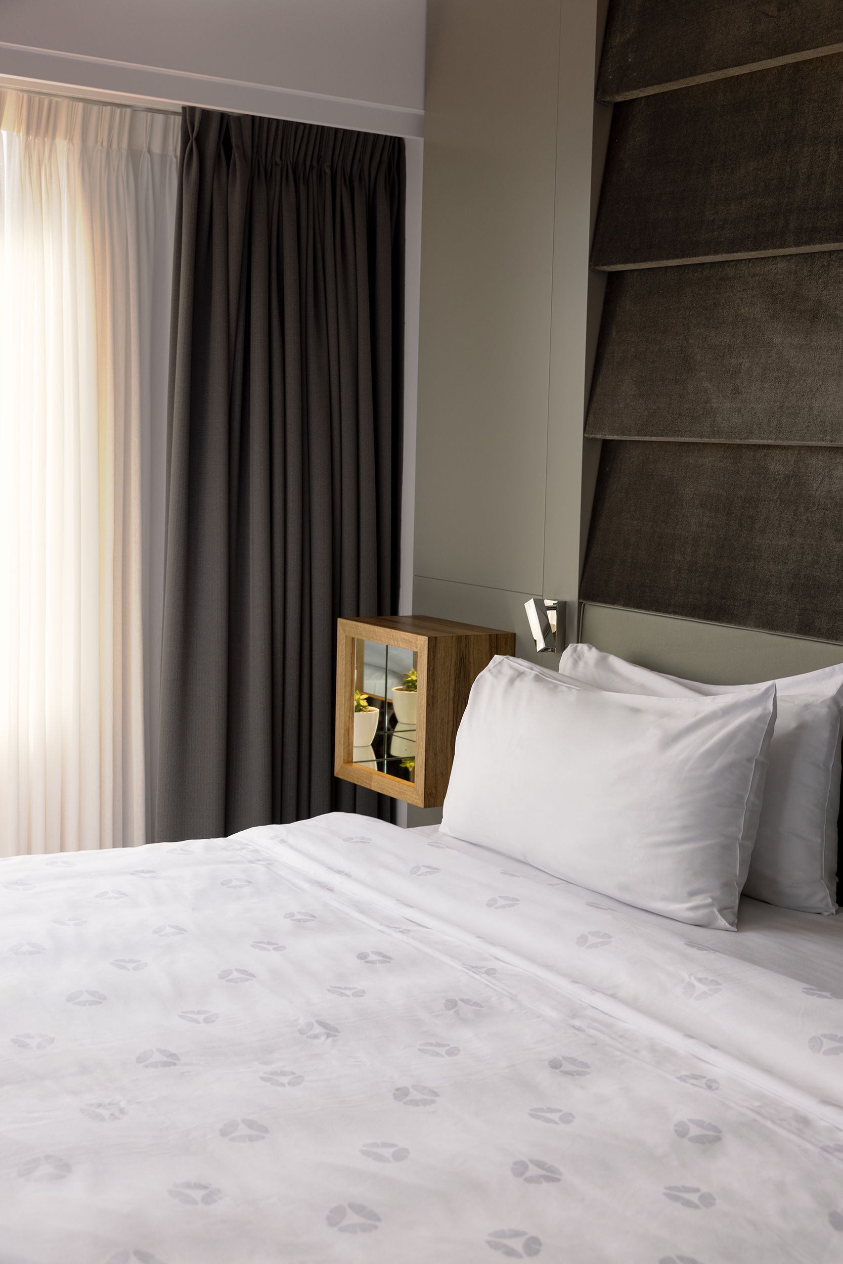 Er staat een bed met witte lakens en kussens in een hotelkamer.