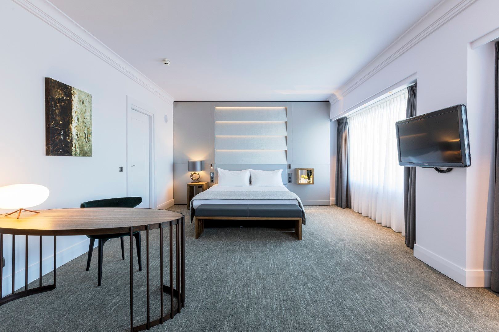 A hotel room with a large bed , desk and television.
