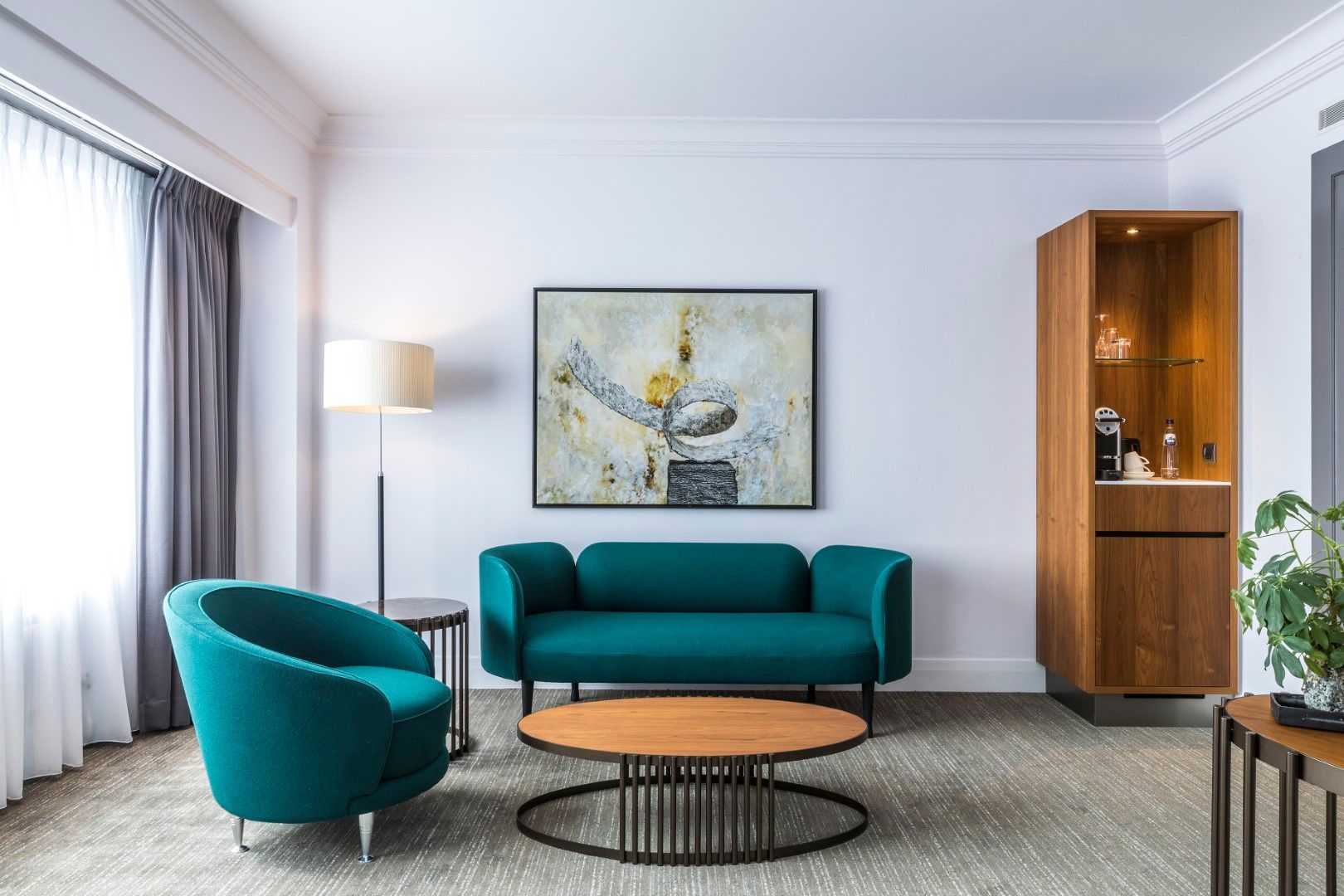 A living room with a couch , chair , coffee table and a painting on the wall.