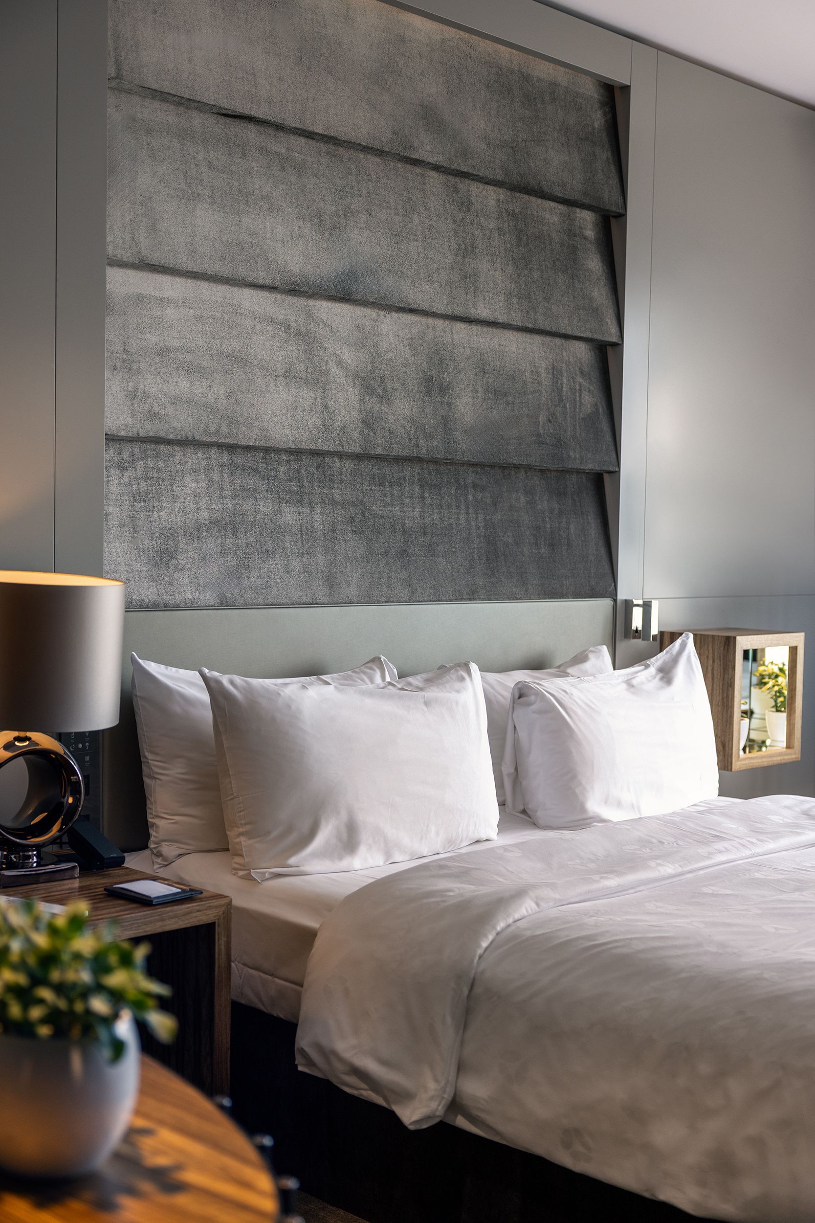 A bed with white sheets and pillows in a hotel room.