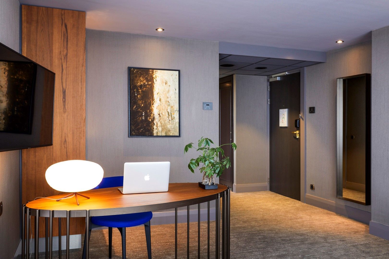 A hotel room with a desk and chair with a laptop on it.