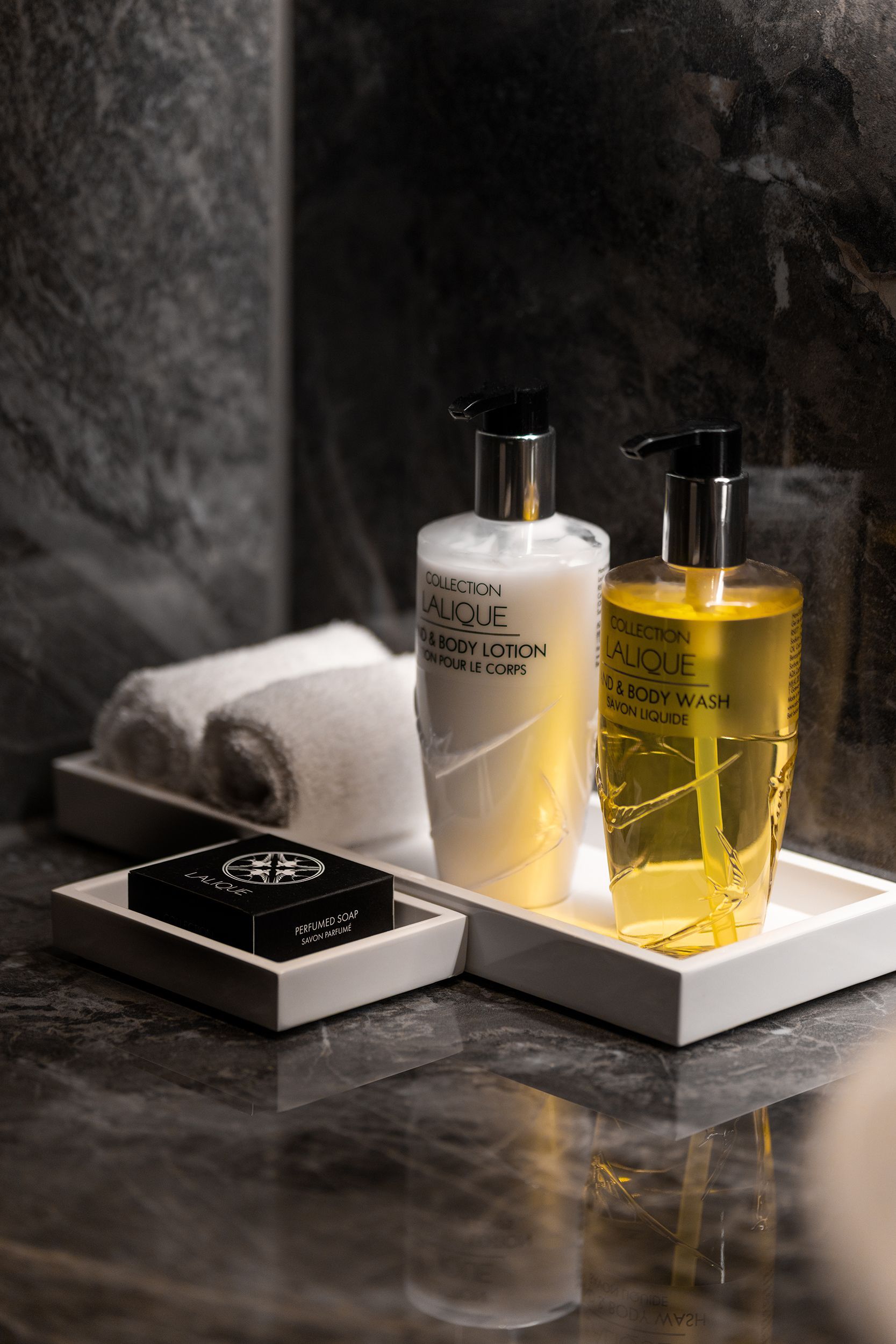 Two bottles of lotion and a bar of soap are on a tray in a bathroom.