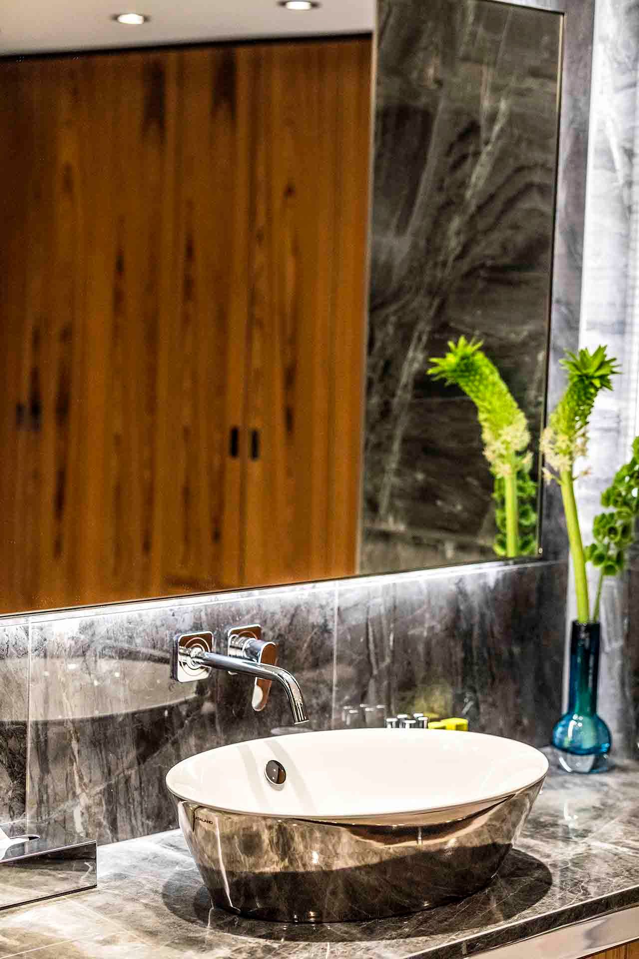 A bathroom with a sink , mirror and wooden cabinets.