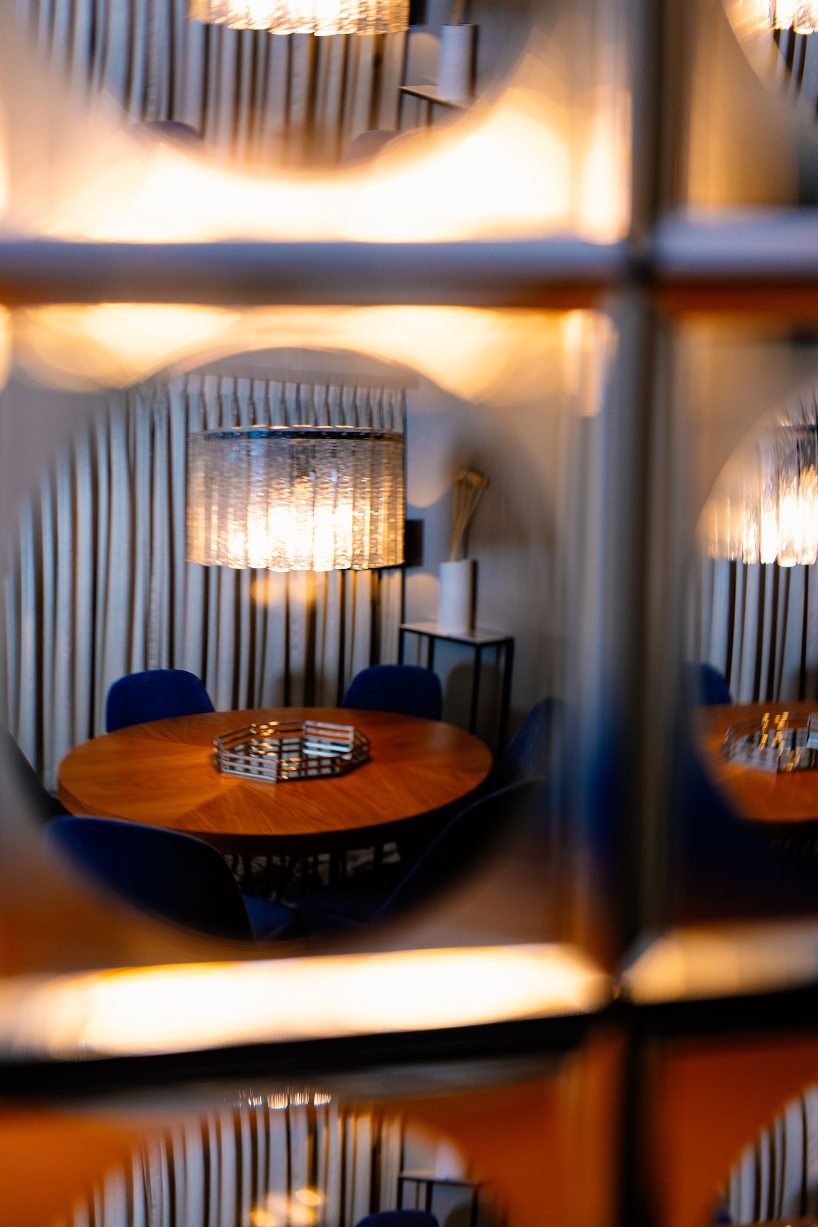 A room with a round table and chairs is reflected in a mirror.