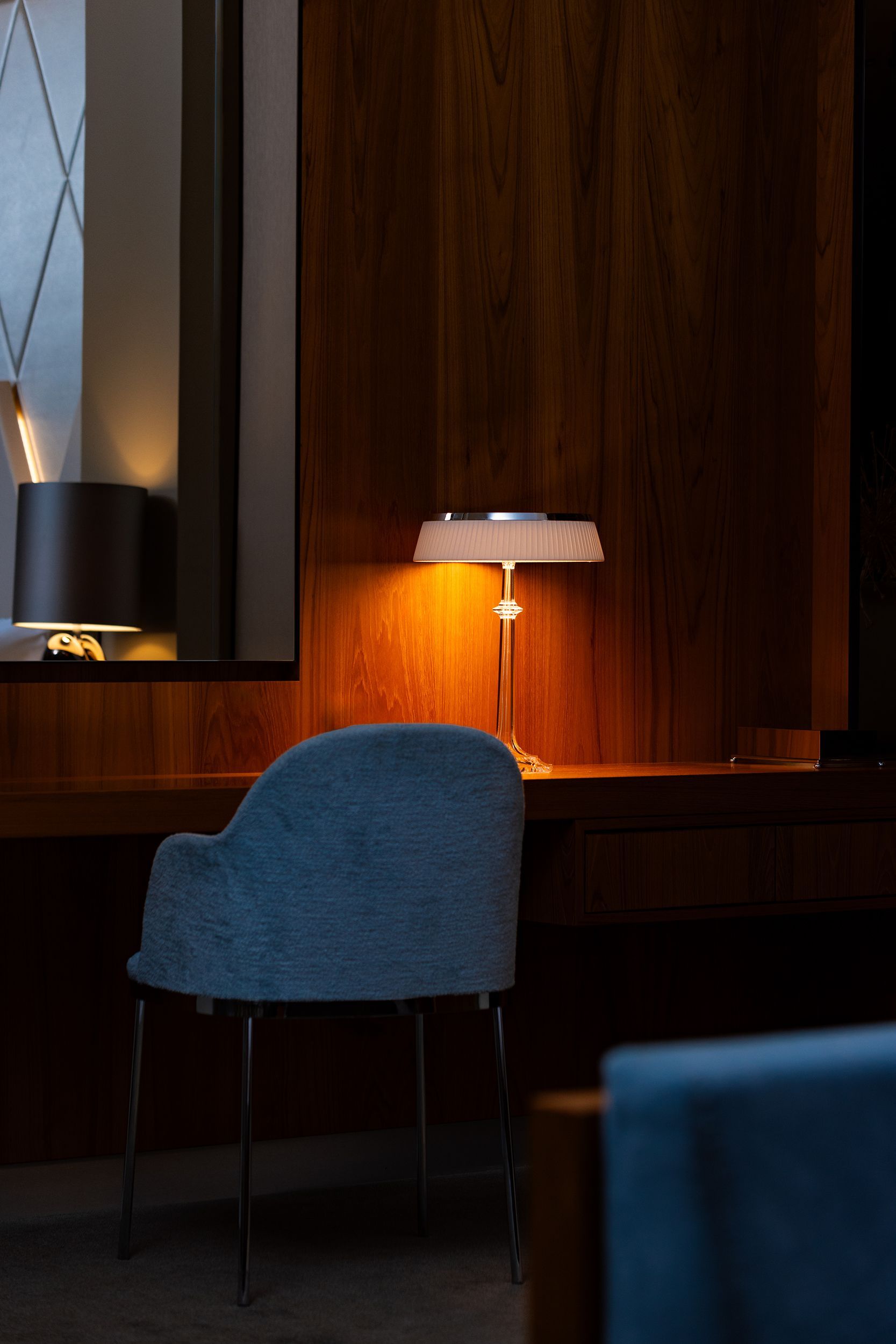 A desk with a lamp and a chair in a dark room.