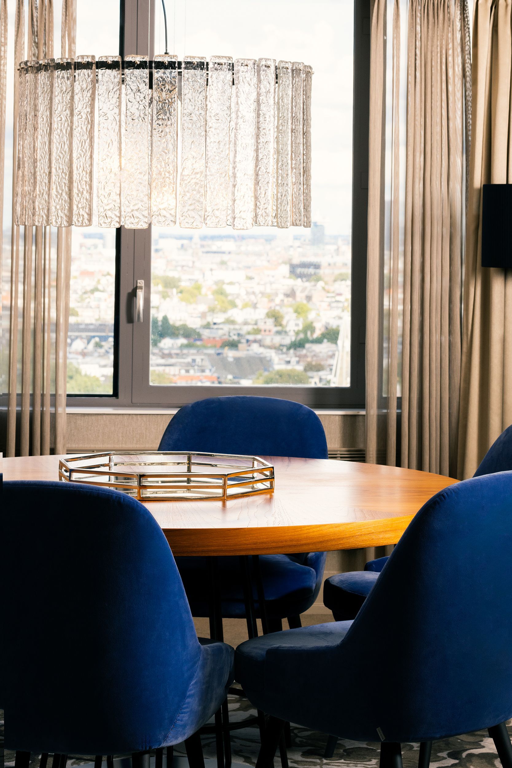 A dining room with a table and chairs in front of a window.